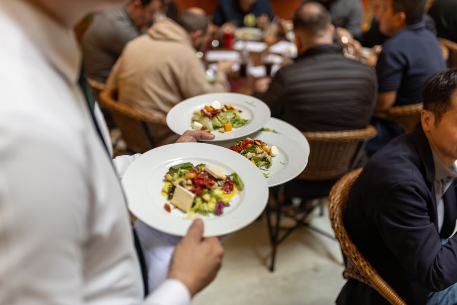 Mesero llevando platillos como referencia para pantallas de promociones en restaurante