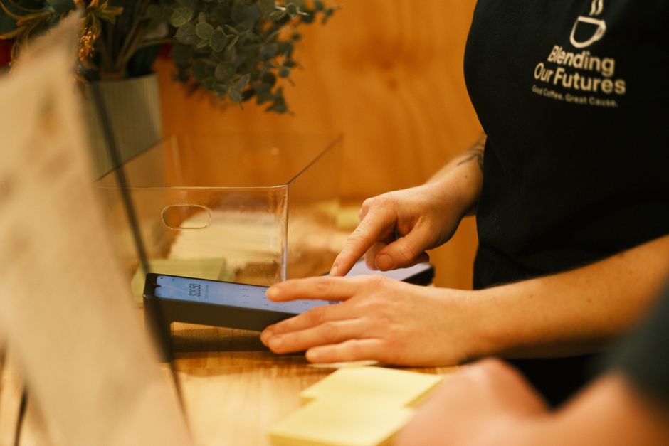 Barista usando una terminal digital para administrar la operación de una cafetería
