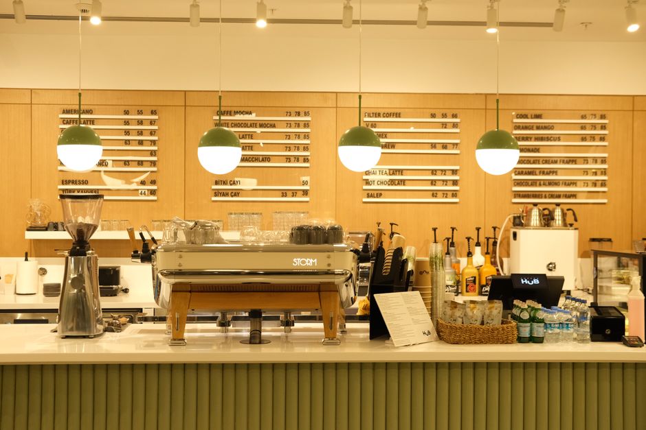 Cafe counter with warm menu-board lighting over espresso equipment