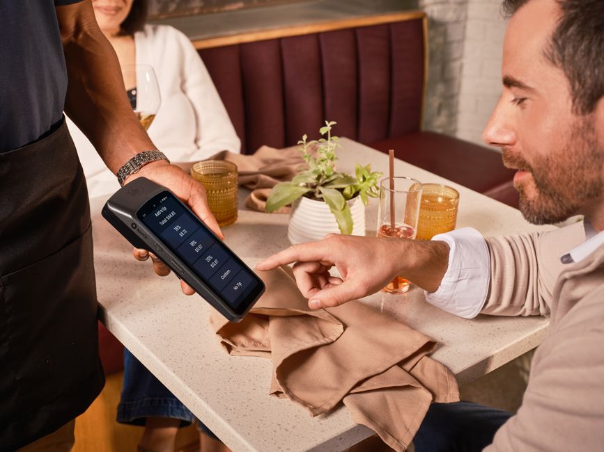 A restaurant guest reviewing a digital payment screen at the table
