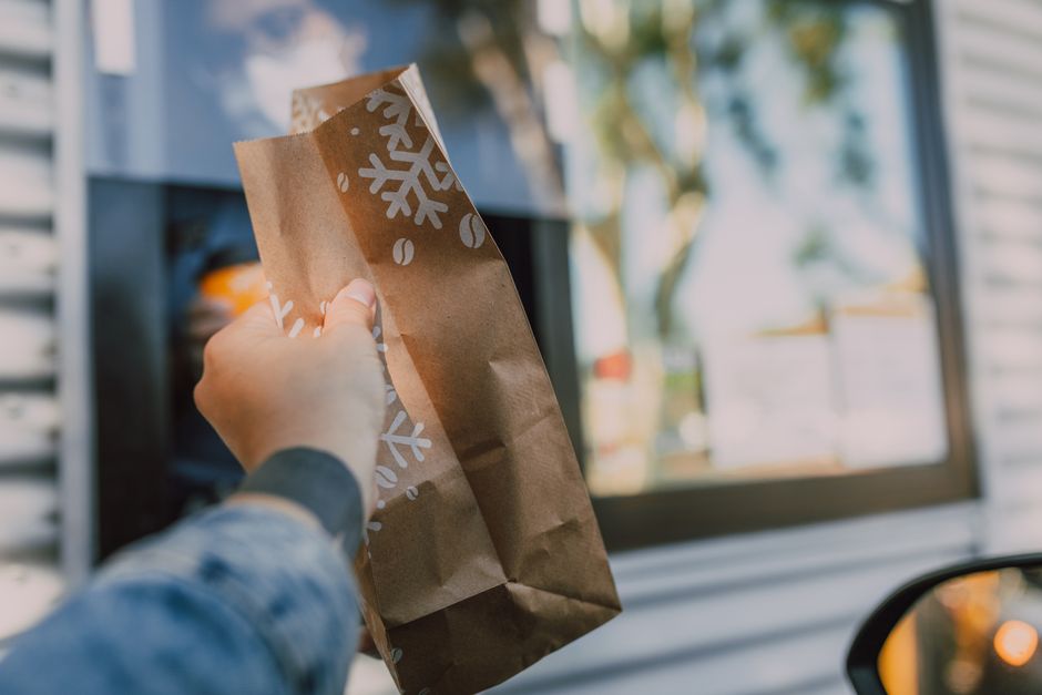 A restaurant employee handing a paper bag through a drive-through window