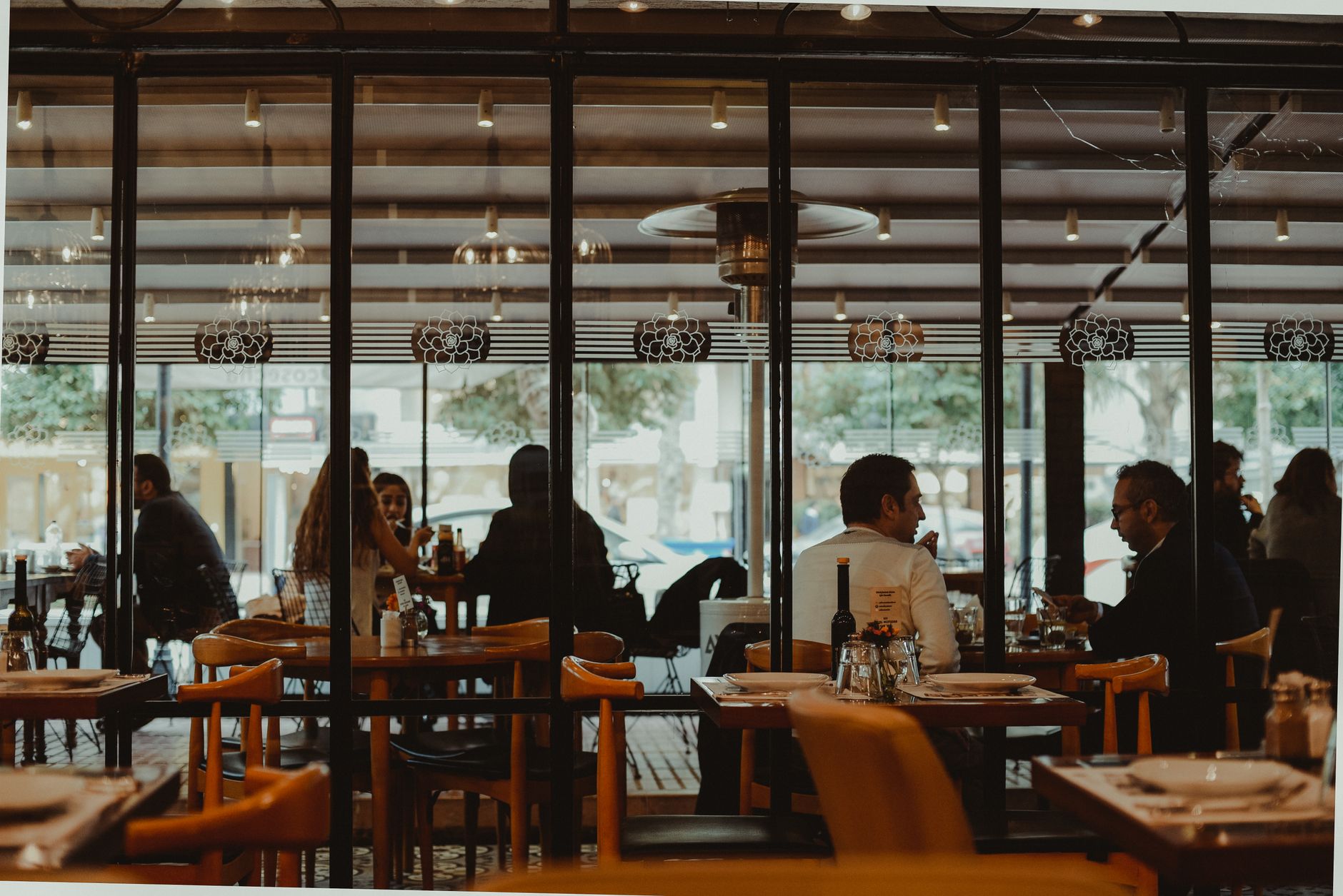 Restaurant guests dining behind glass, representing real screen-count planning before choosing Fugo pricing