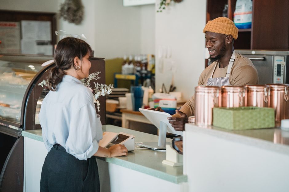 Barista atendiendo a una clienta para evaluar pantallas cerca del mostrador
