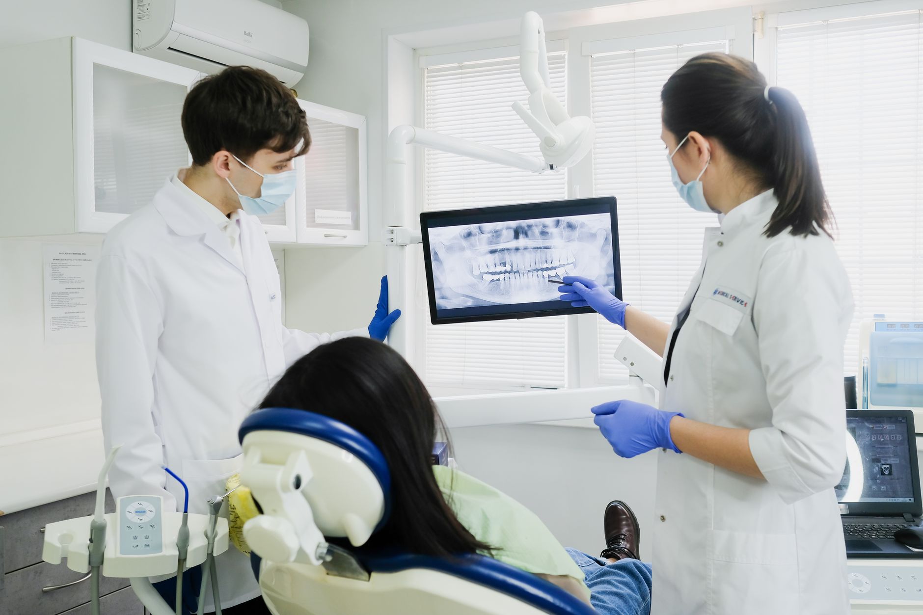 Dentistas explican una radiografía a una paciente en un consultorio dental