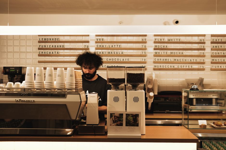 Barista trabajando bajo el menú de una cafetería