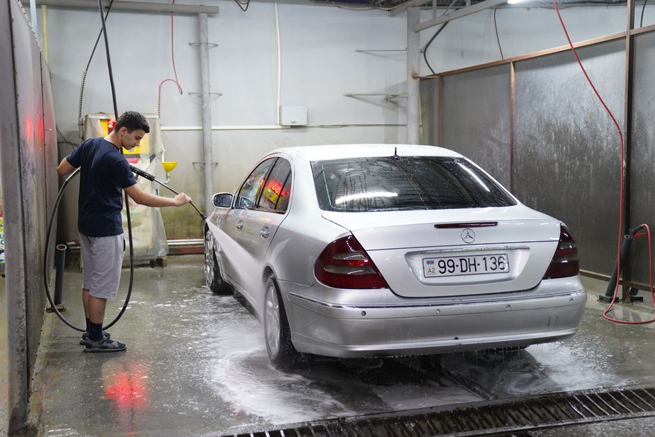 Trabajador lavando un auto dentro de una bahía de servicio