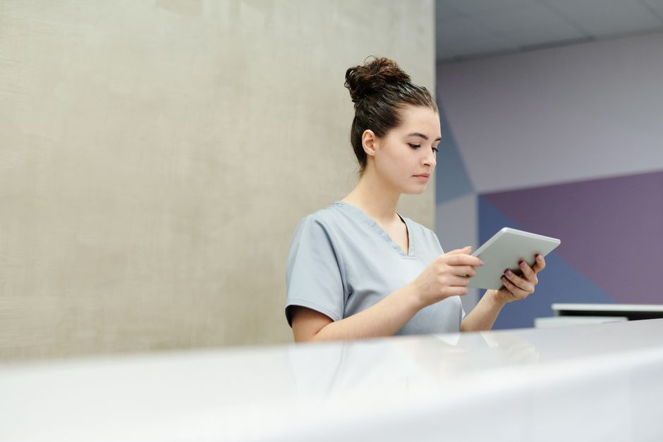Recepcionista de clínica usando una tablet para actualizar avisos de pantalla