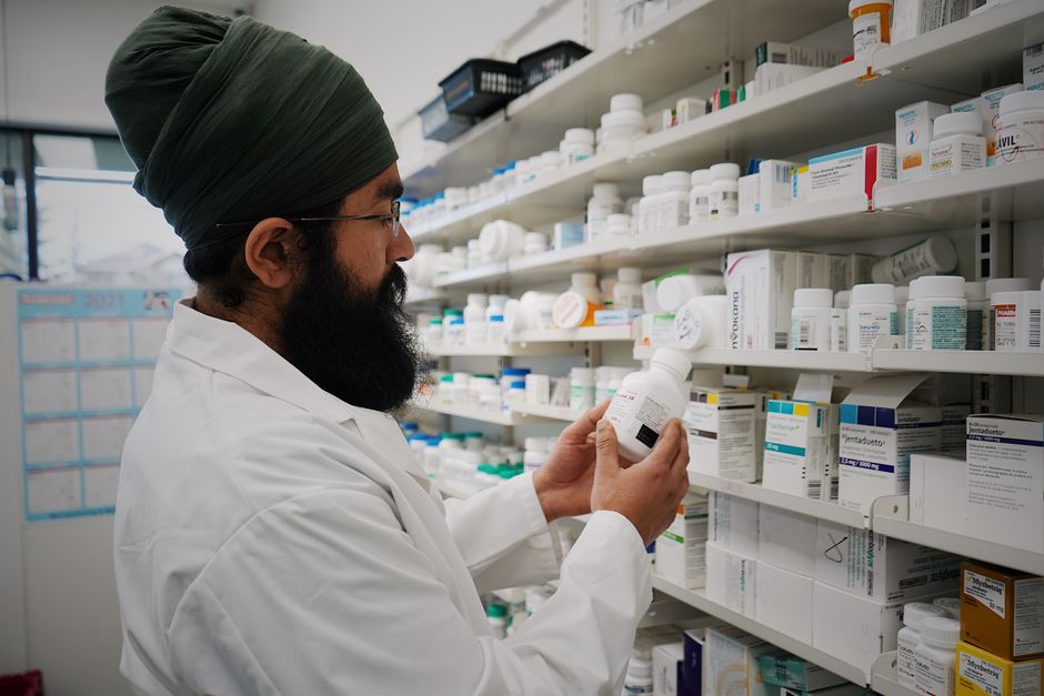 Farmacéutico revisando medicamentos en anaqueles para pantallas digitales farmacia México