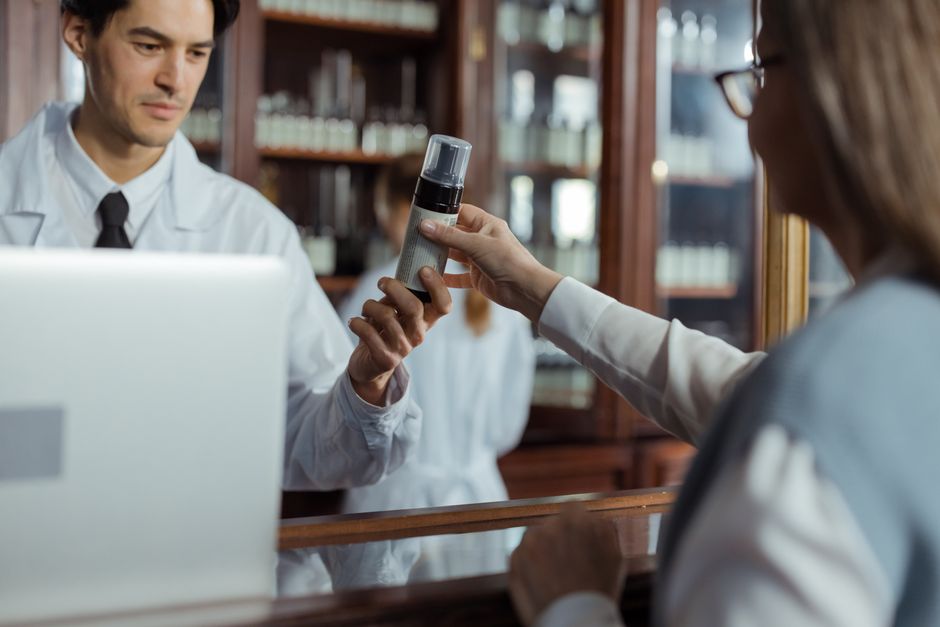 Farmacéutico entregando producto a una cliente en mostrador