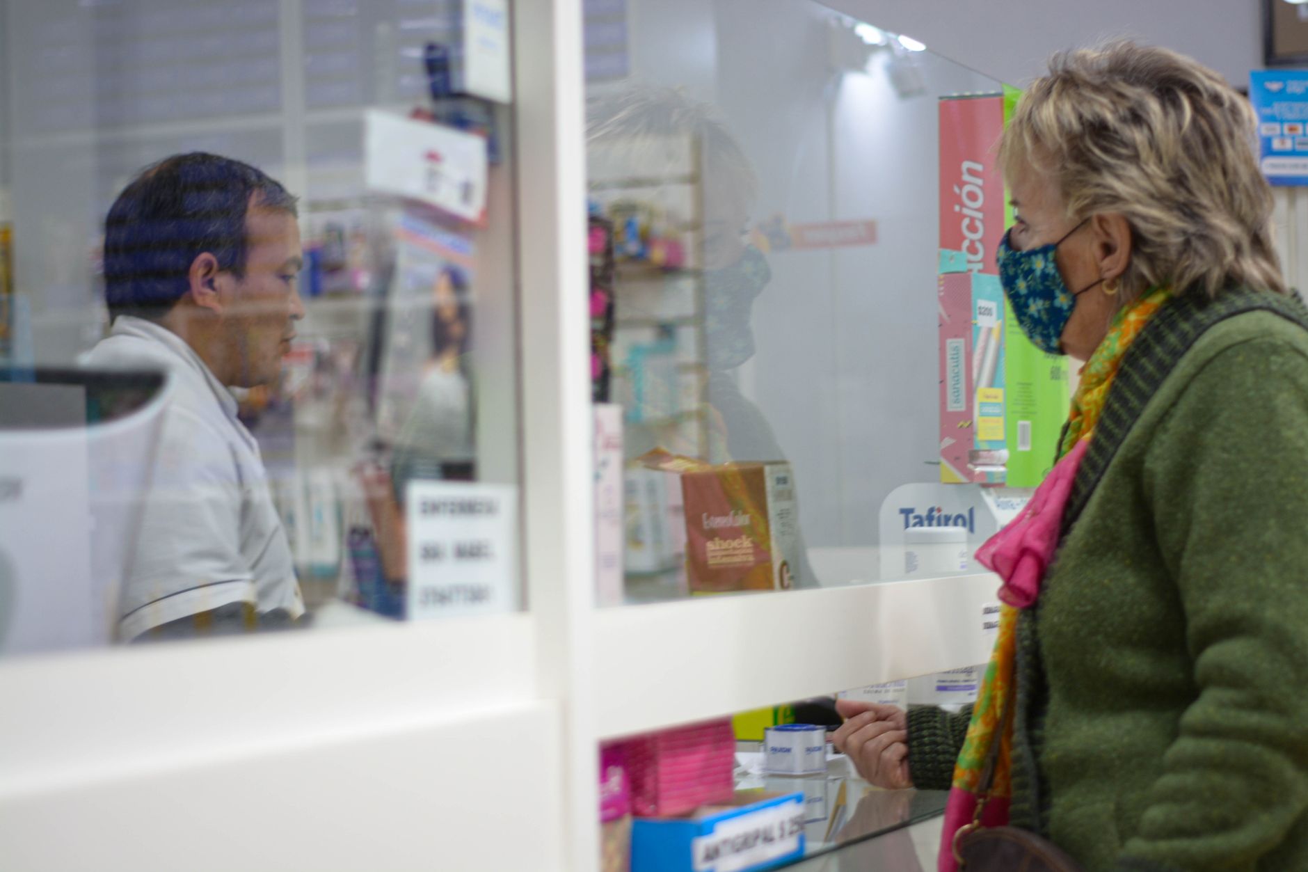 Cliente atendida en mostrador de farmacia para planear señalización digital para farmacias