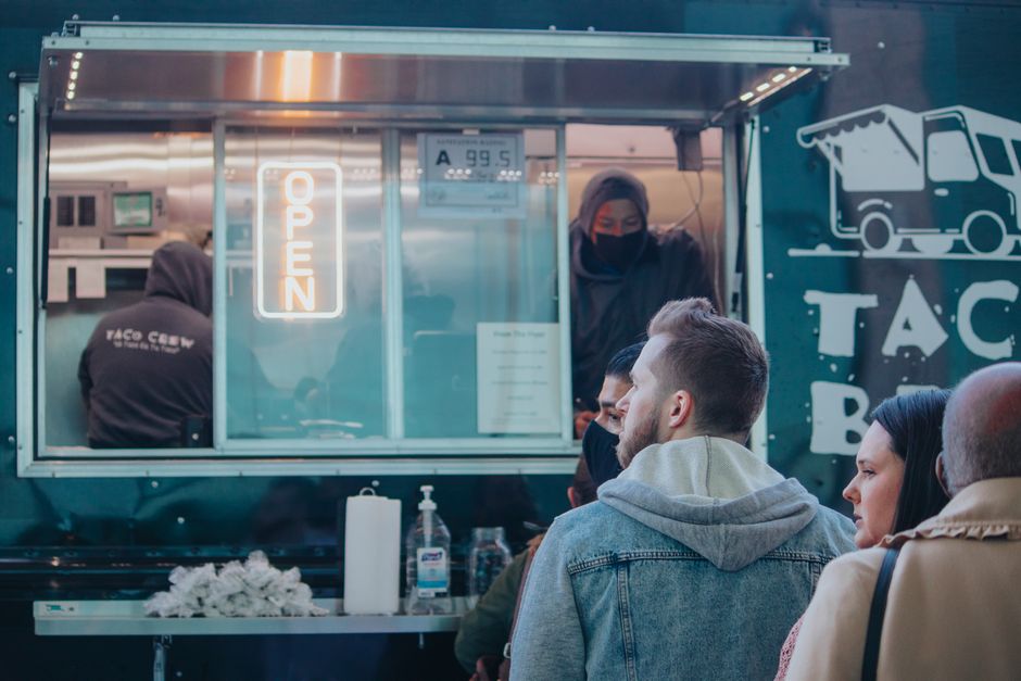 Clientes consultando opciones antes de ordenar comida en un entorno urbano