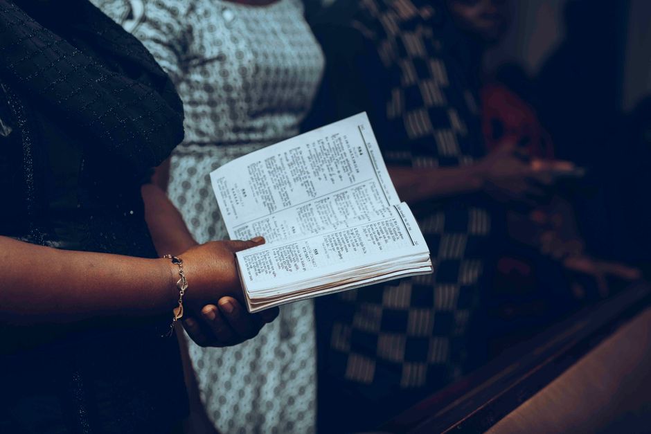 Personas siguiendo cantos en un servicio religioso como referencia para letras en pantalla