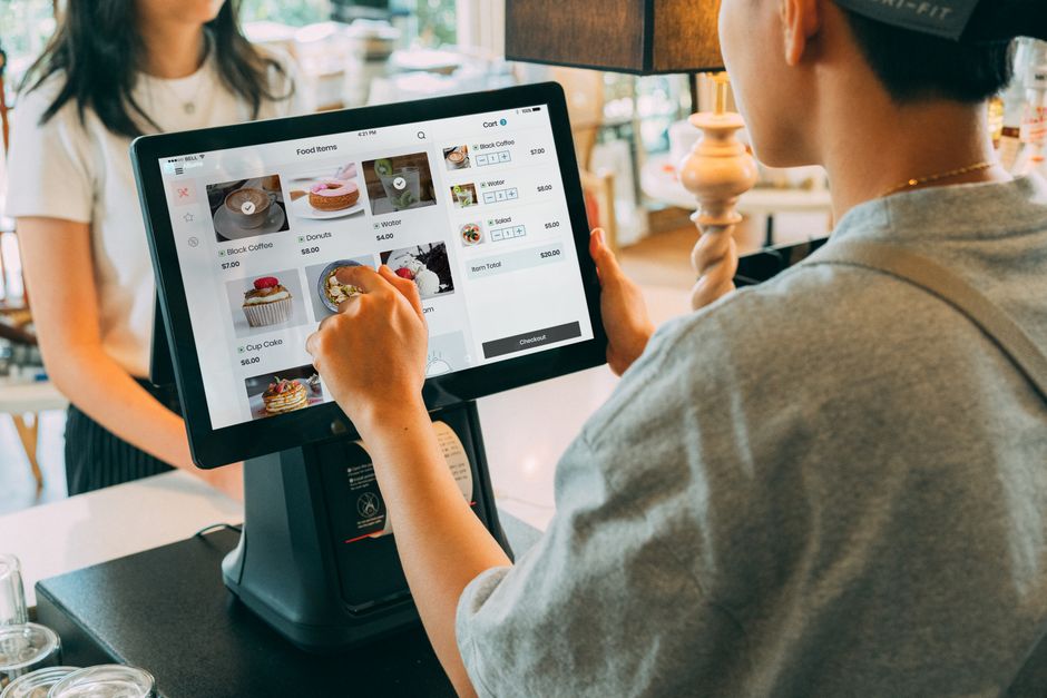 Cajera usando terminal en mostrador para planear promociones digitales en punto de venta