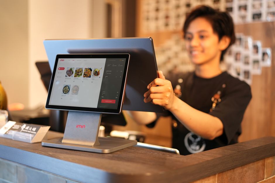 Restaurant staff member helping customers at a counter with a POS screen