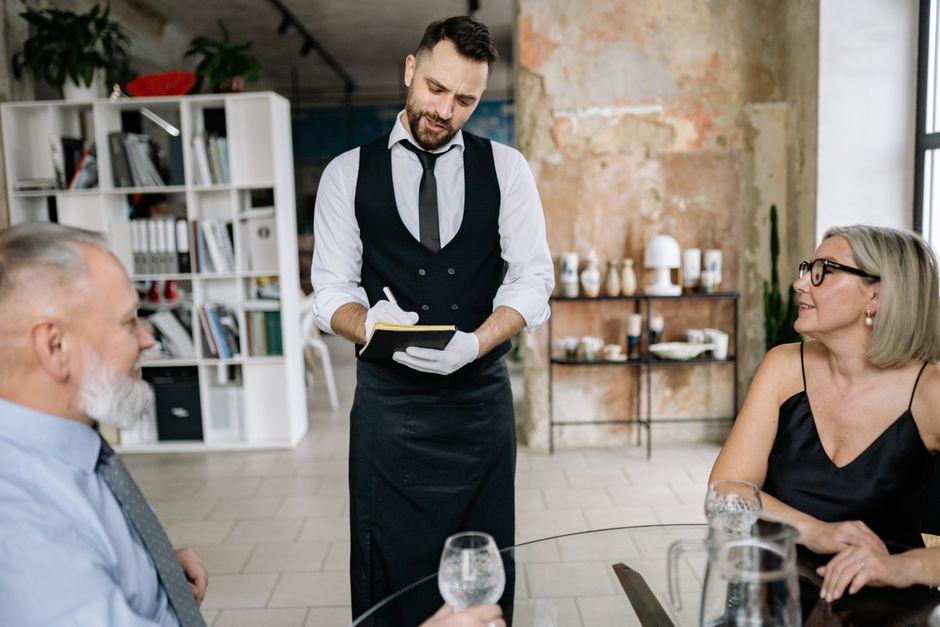 Waiter using a tablet during restaurant service, representing staff-owned signage updates