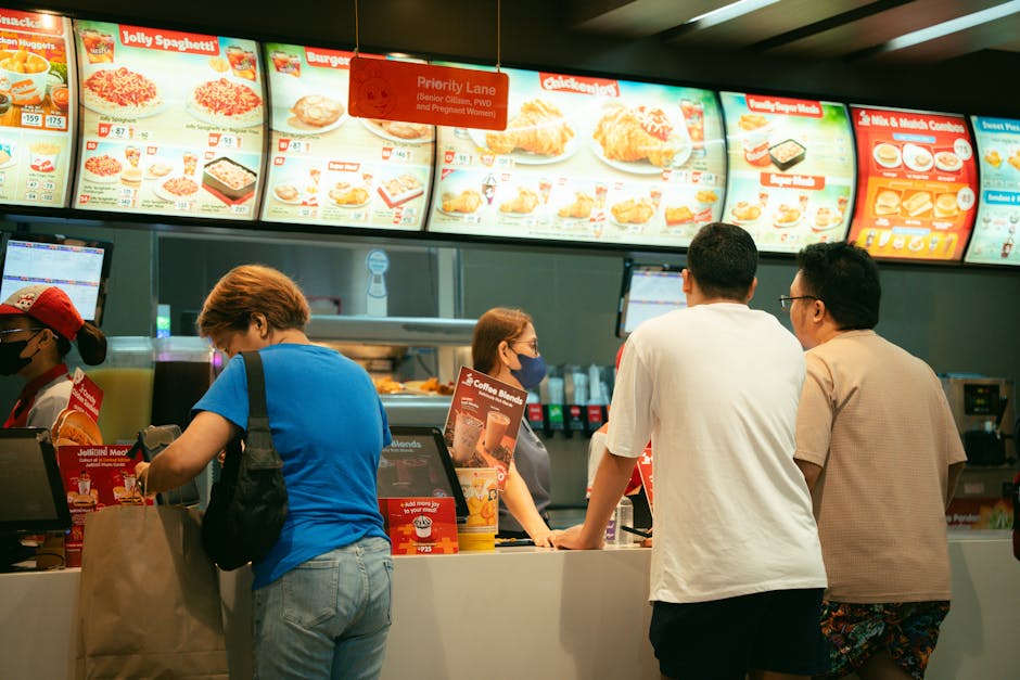 Customers ordering at a fast-food restaurant counter with visible menu-board context